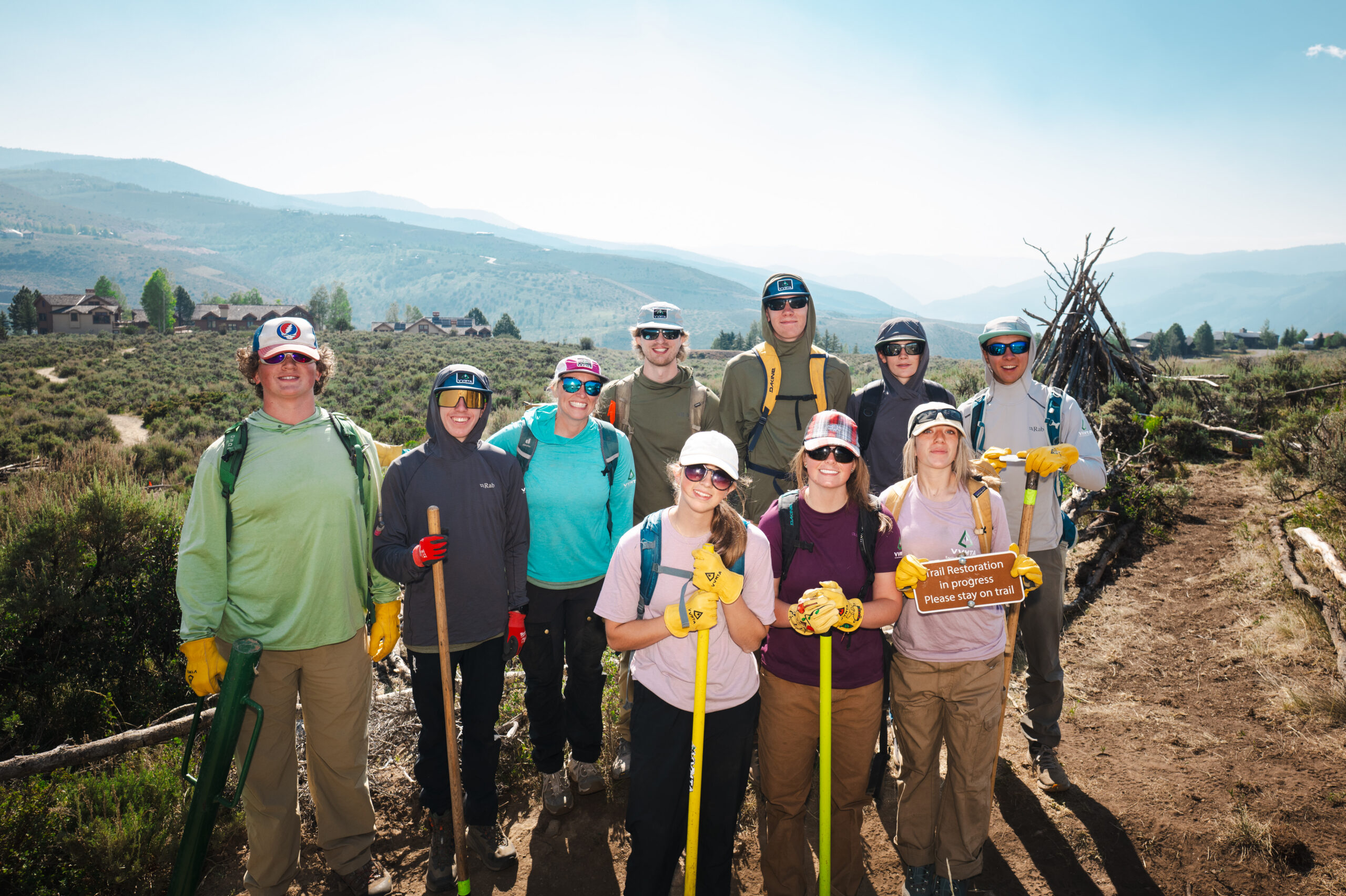 Eagle County Youth Corps crew posing on a restored trail with a "Trail Restoration in progress" sign