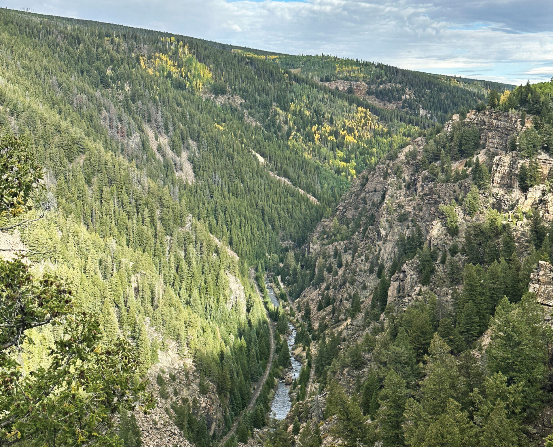 Overhead view of the Tennessee Pass rail corridor following a river through a forested Colorado canyon