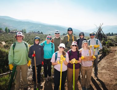 Eagle County Youth Corps crew posing on a restored trail with a "Trail Restoration in progress" sign