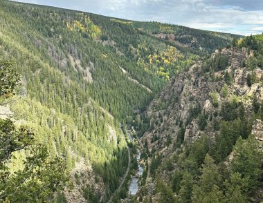 Overhead view of the Tennessee Pass rail corridor following a river through a forested Colorado canyon